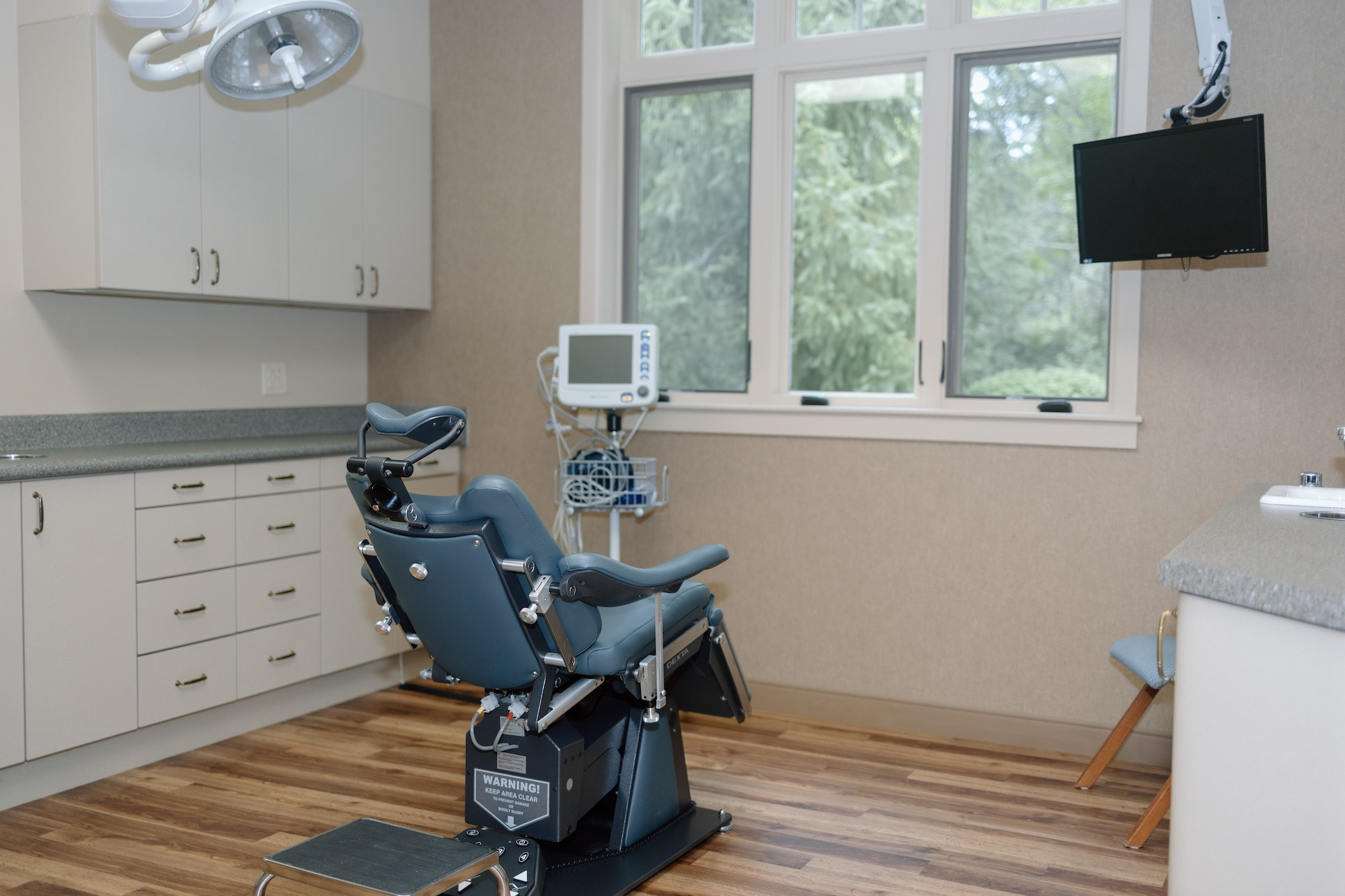 This is a photograph of an interior dental office space with a modern chair, equipment, and a window.