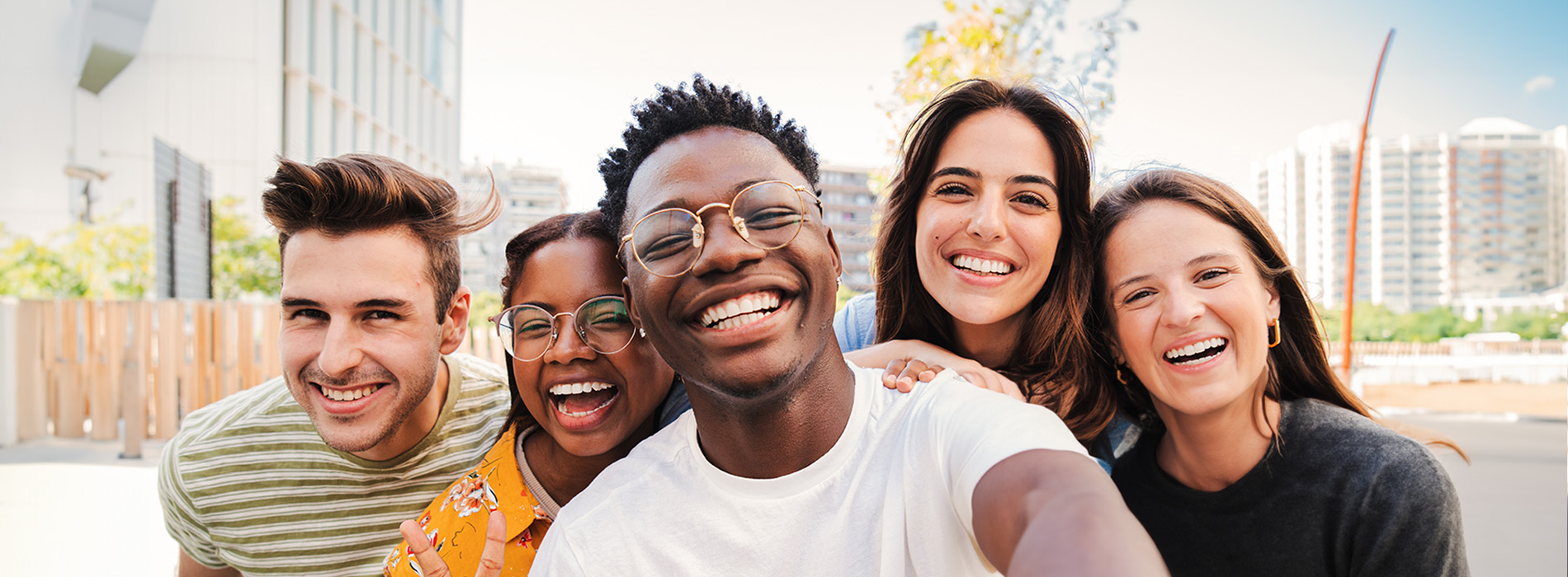 The image is a collage of four separate photographs featuring young adults smiling and posing for the camera, with one individual on the left side of the frame appearing to be in a different setting than the others.