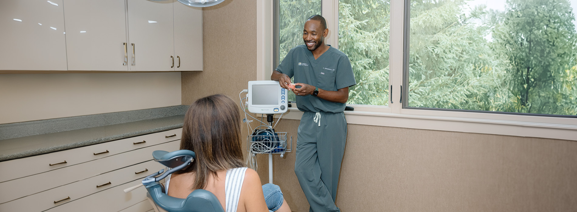 A dental hygienist is assisting a patient with a dental chair.