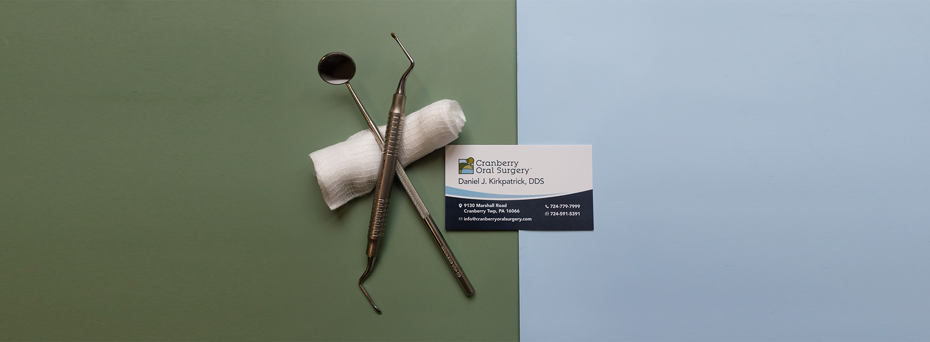 The image shows a collection of objects, including a toothbrush, a pair of scissors, and a small container with a blue label, all resting on a surface against a green background.