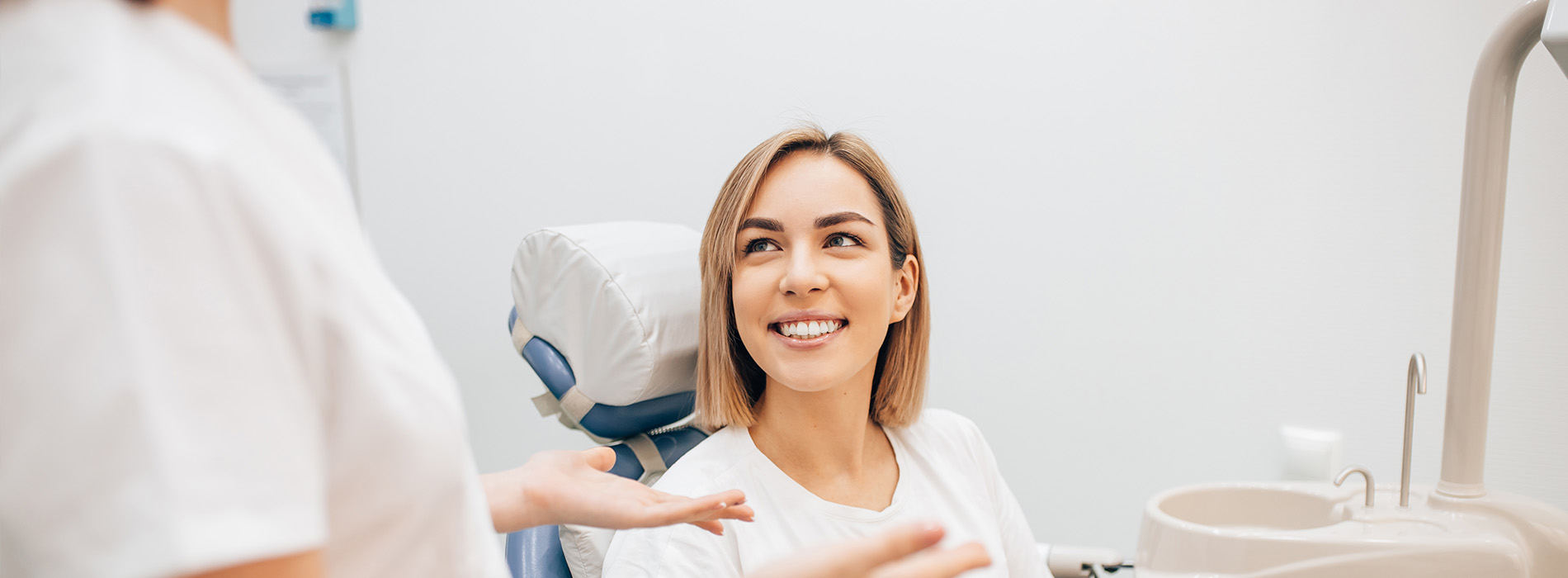 A dental hygienist is assisting a patient in a dental chair.