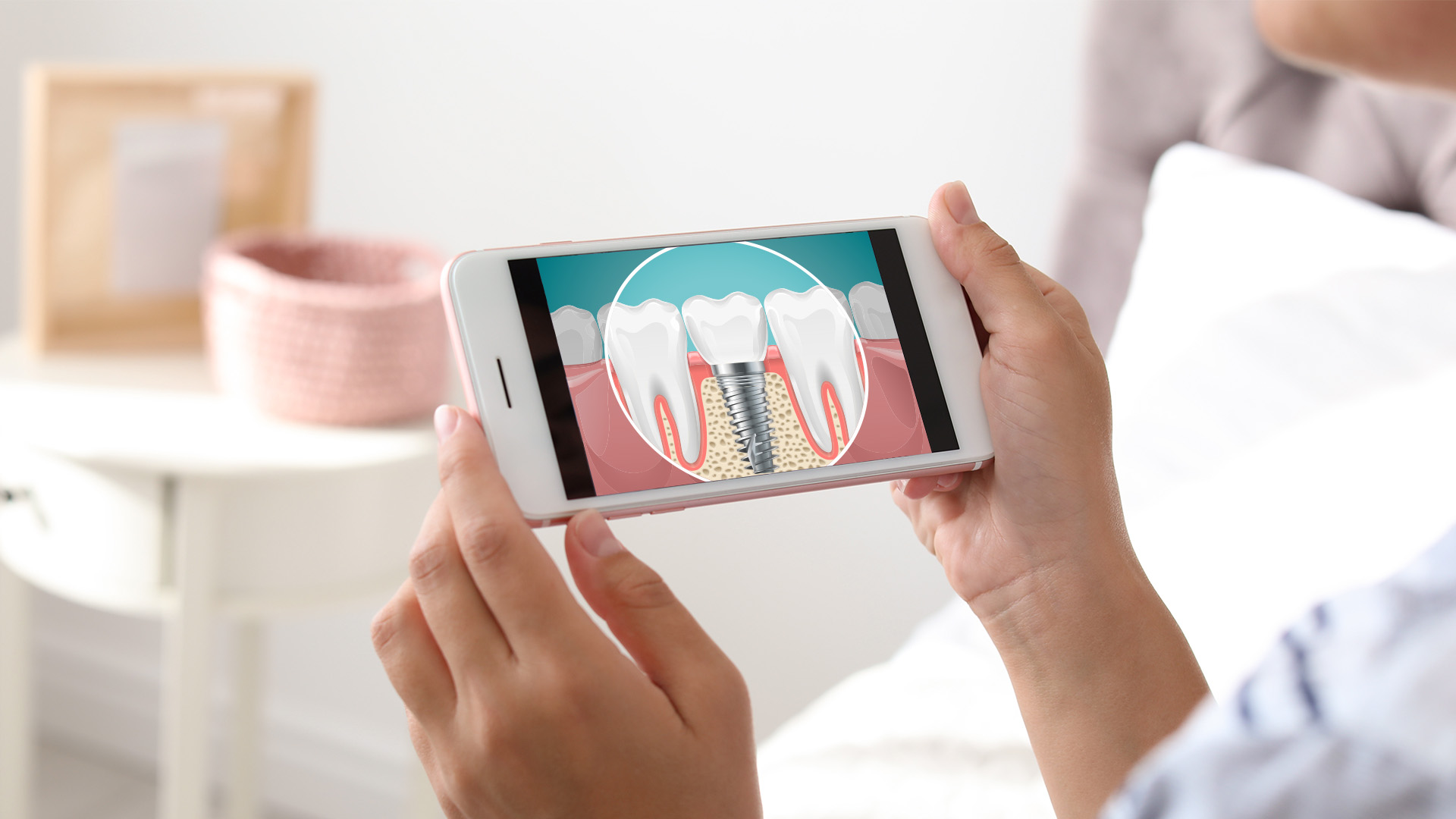 A person holding a smartphone displaying an image of a tooth with a magnified view showing the root and pulp chamber.