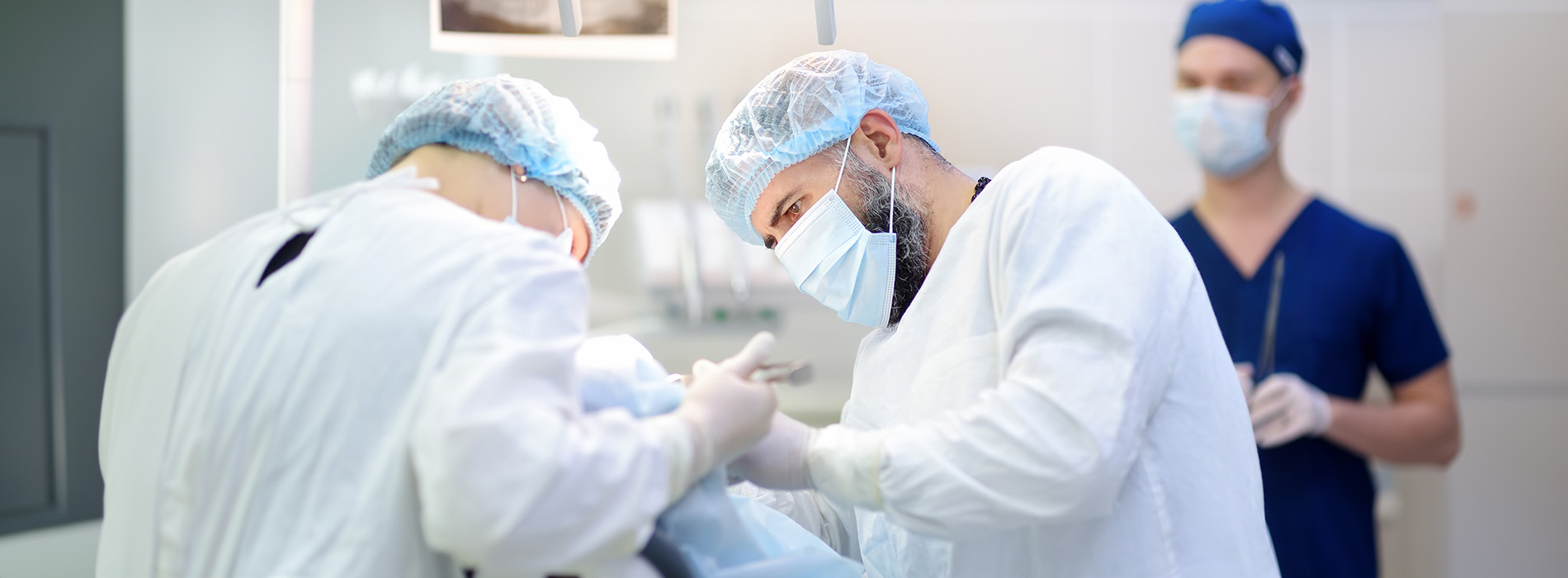 Medical professionals in a sterile environment, with one person operating on another.