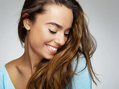 A smiling woman with long hair, looking to her side.