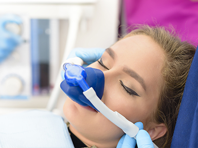 A person being attended to by a medical professional, with a blue oxygen mask covering their nose and mouth.